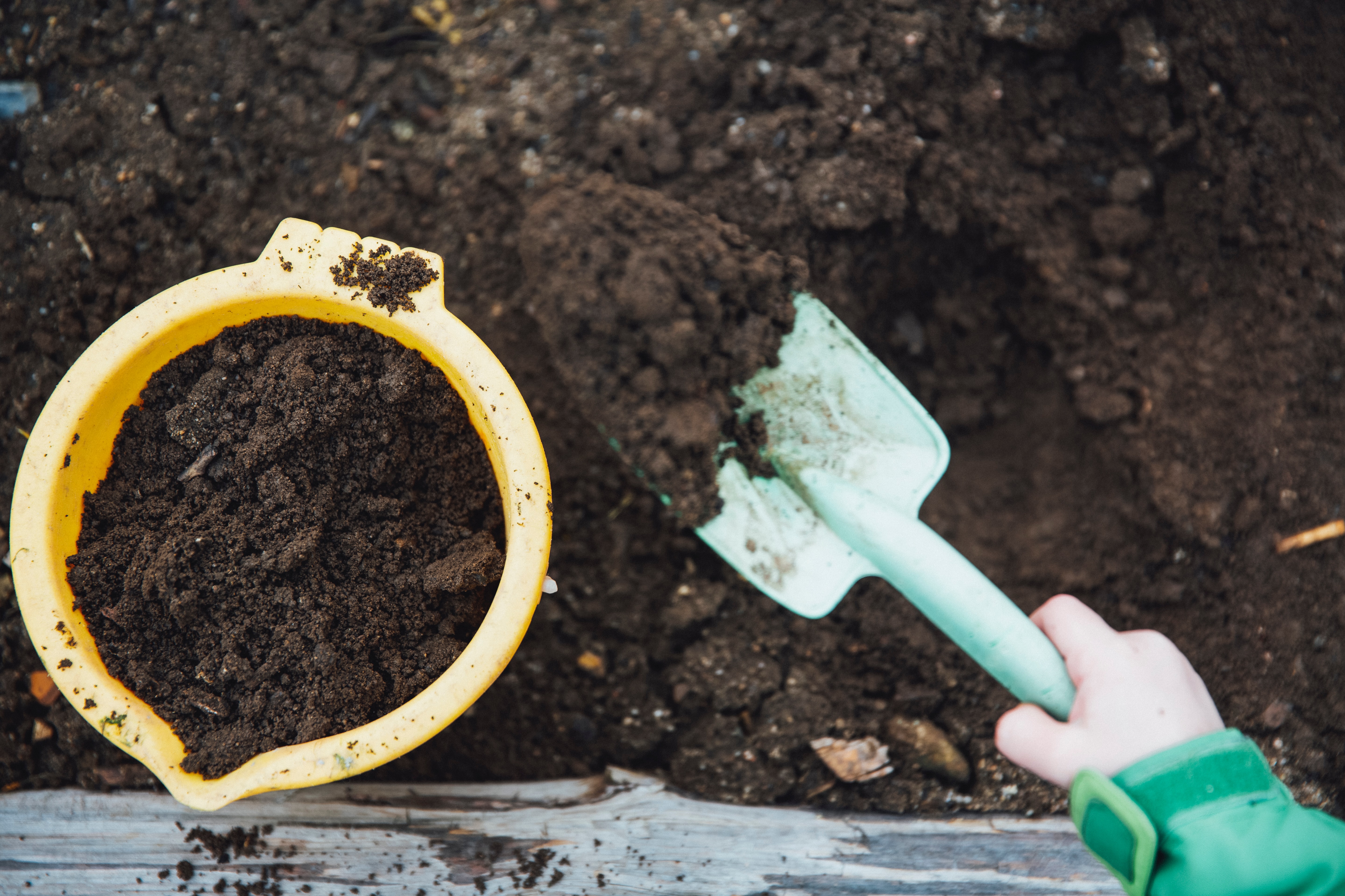 A kid filling a bucket with compost